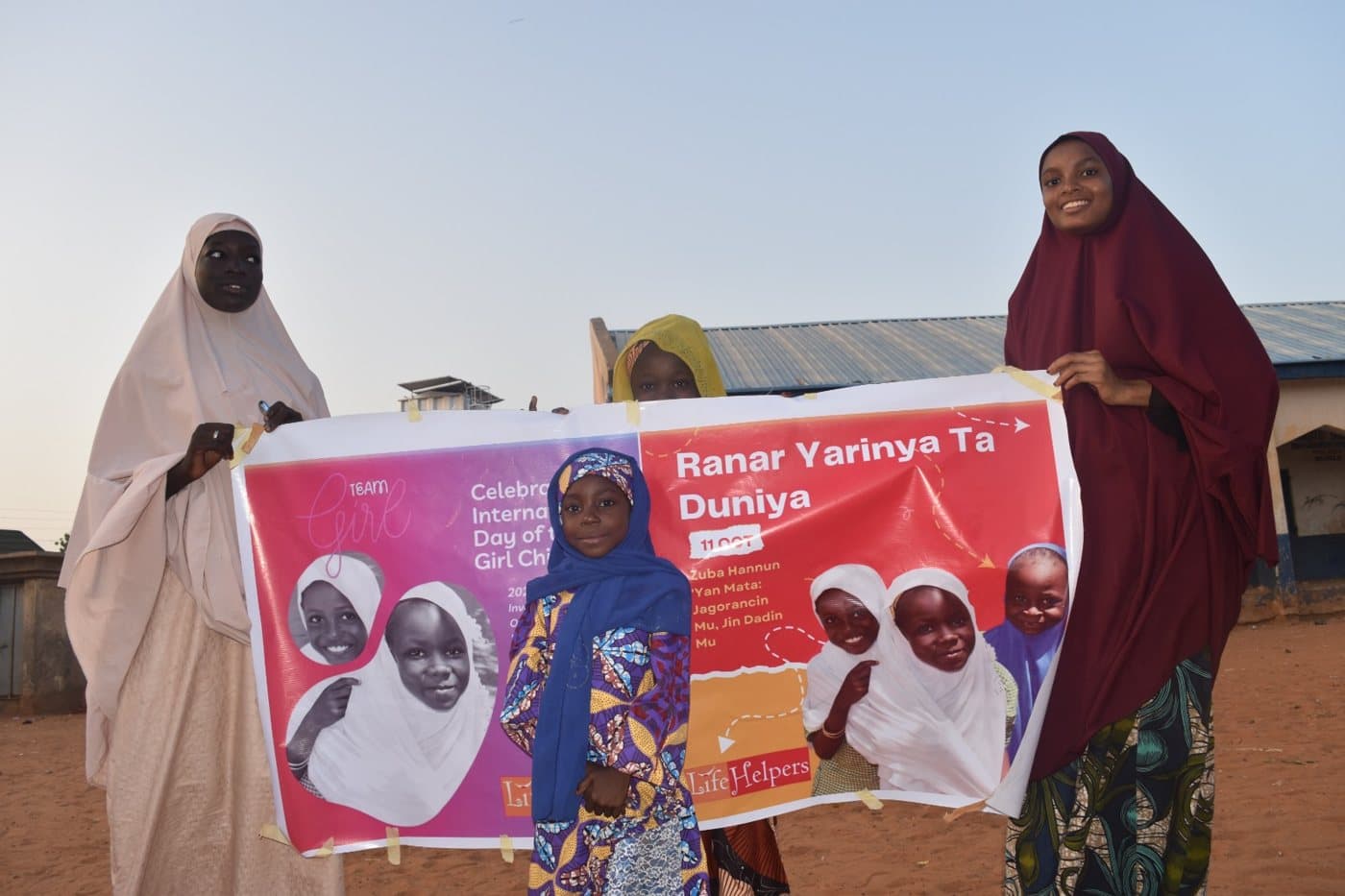 Women holding a “Ranar Yarinya Ta Duniya” International Day of the Girl Child banner