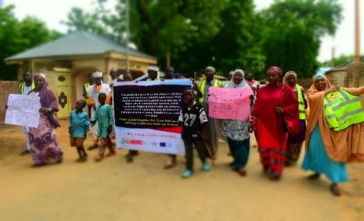 Community members marching with banners and placards against gender-based violence