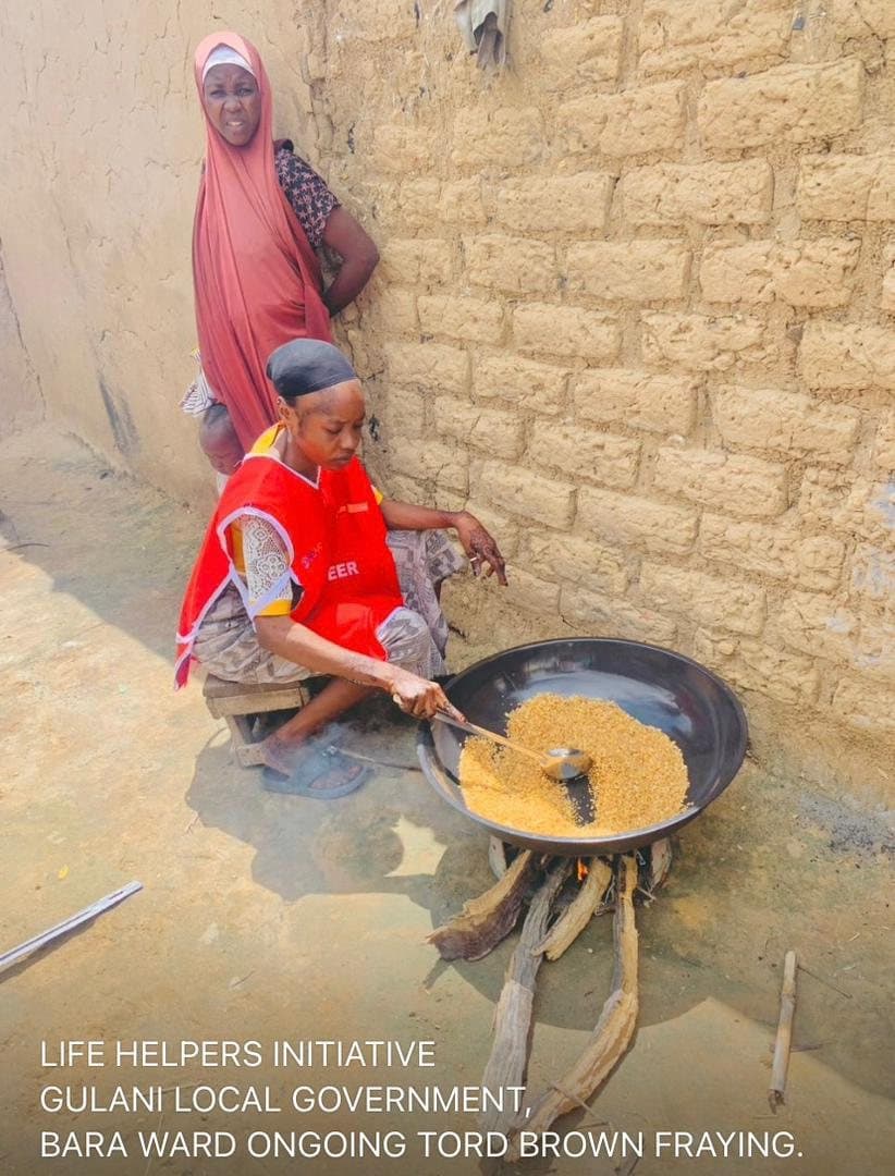 A woman roasting grains for Tom Brown in Bara Ward, Gulani LGA, Yobe State