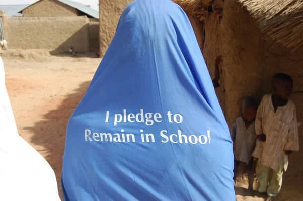 Girl wearing a hijab printed with 'I pledge to remain in school'