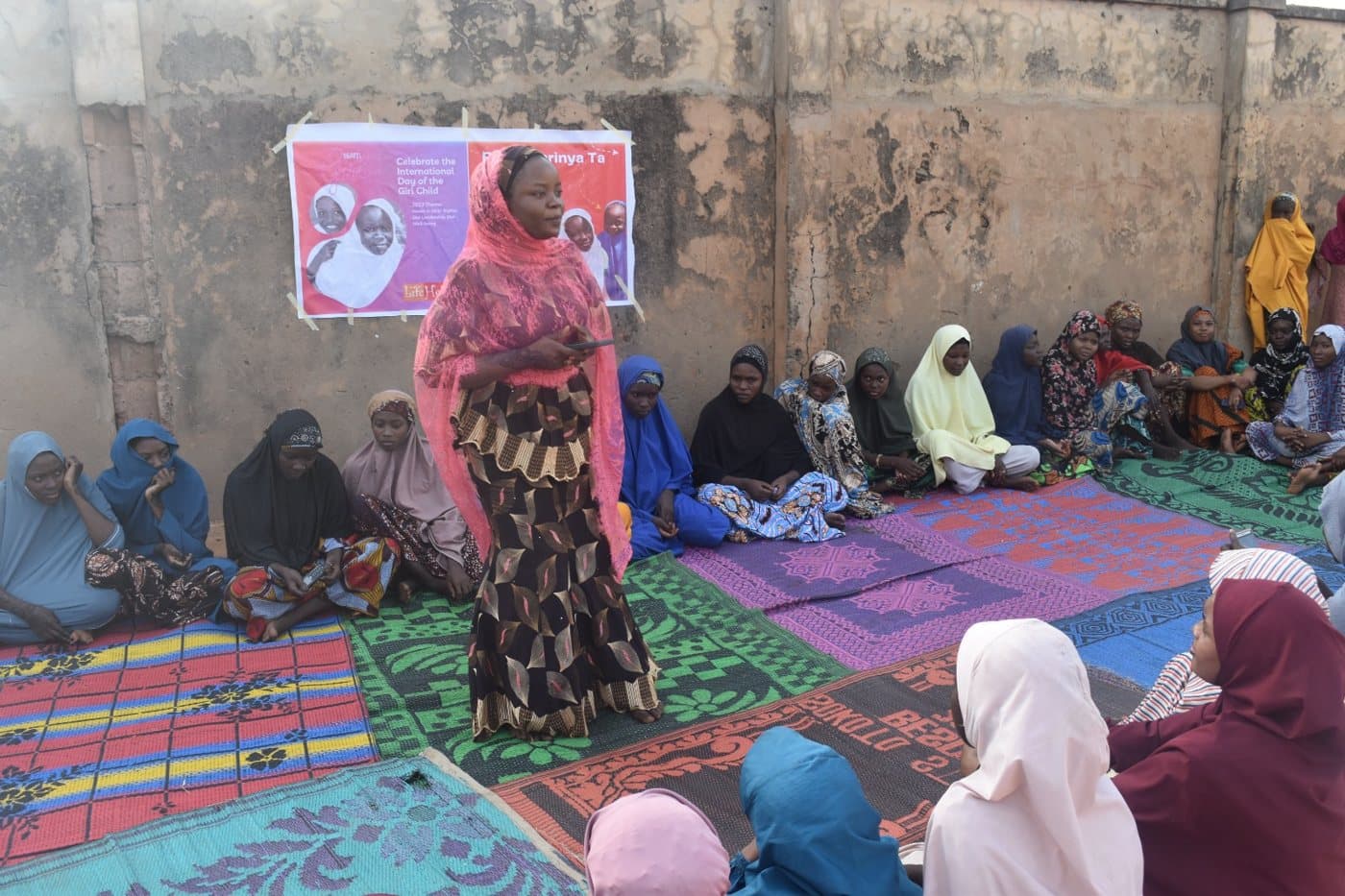 A facilitator speaking to a women's community session under an LHI banner