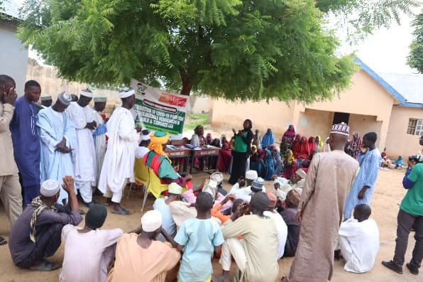 Community members gathered under a tree for an LHI community meeting