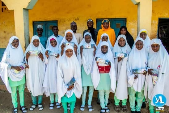 Schoolgirls in white hijabs holding NIDAKE reusable sanitary pad packs